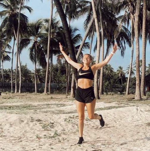 A guest dancing barefoot on the sand between tall palm trees