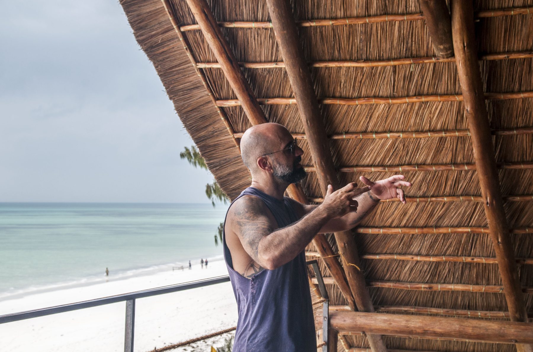 TribeX founder Ala leading a session under a thatched shala facing the sea