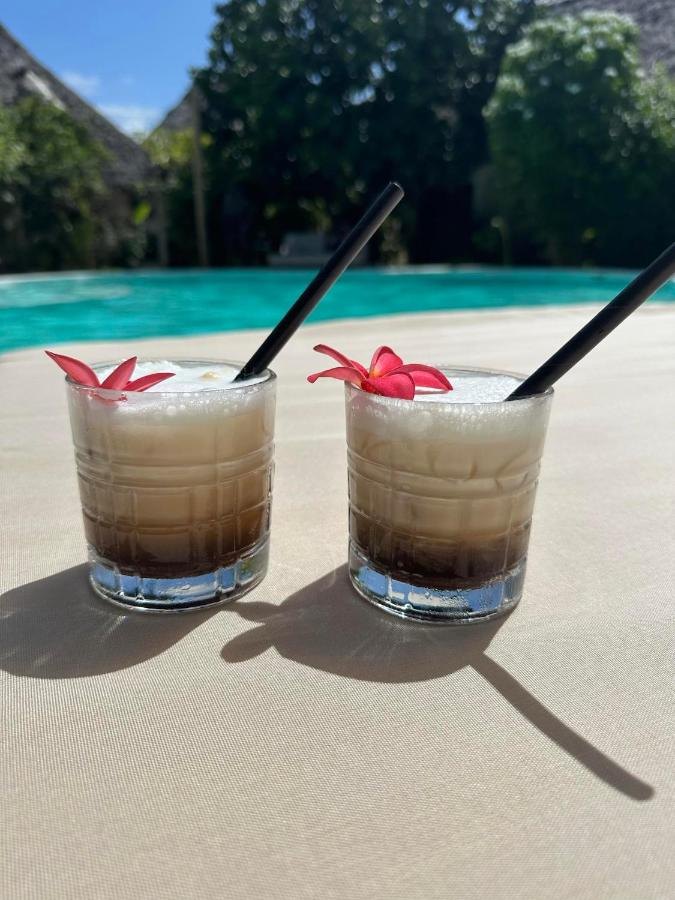 Two fresh coconut drinks on the sand beside the turquoise sea