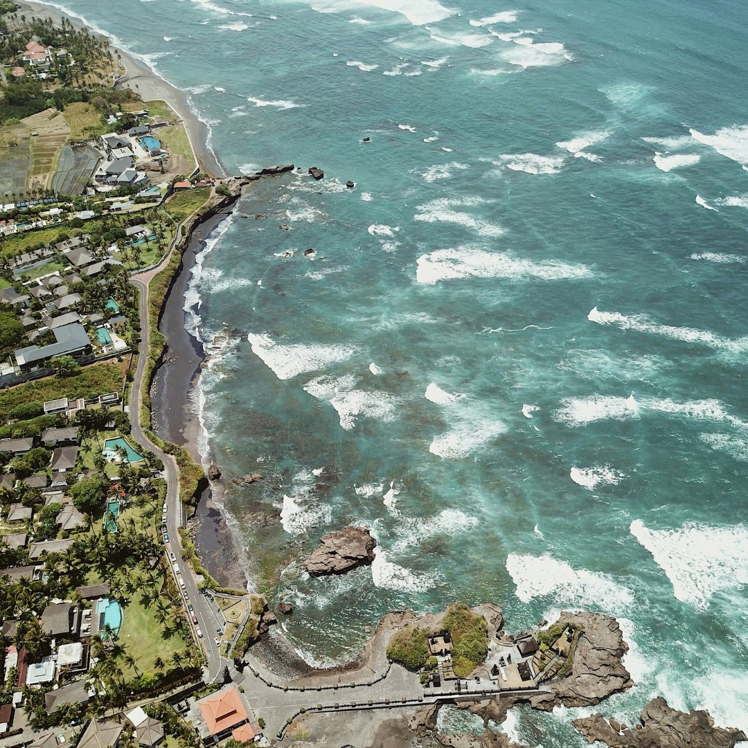 Aerial view of a tropical coastline with waves breaking along the reef